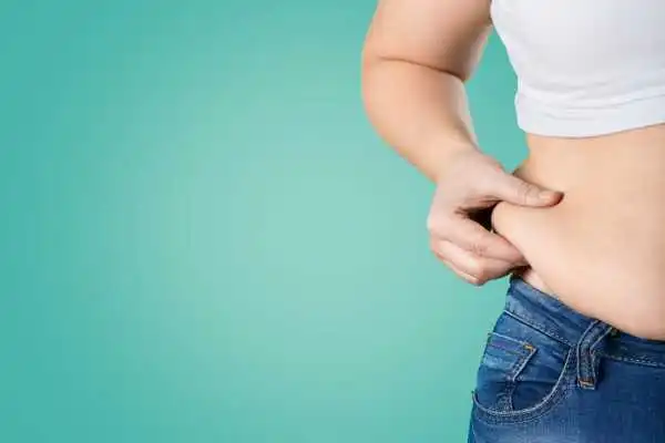 Image of woman pinching her love handles to show weight gain Cambridgeshire